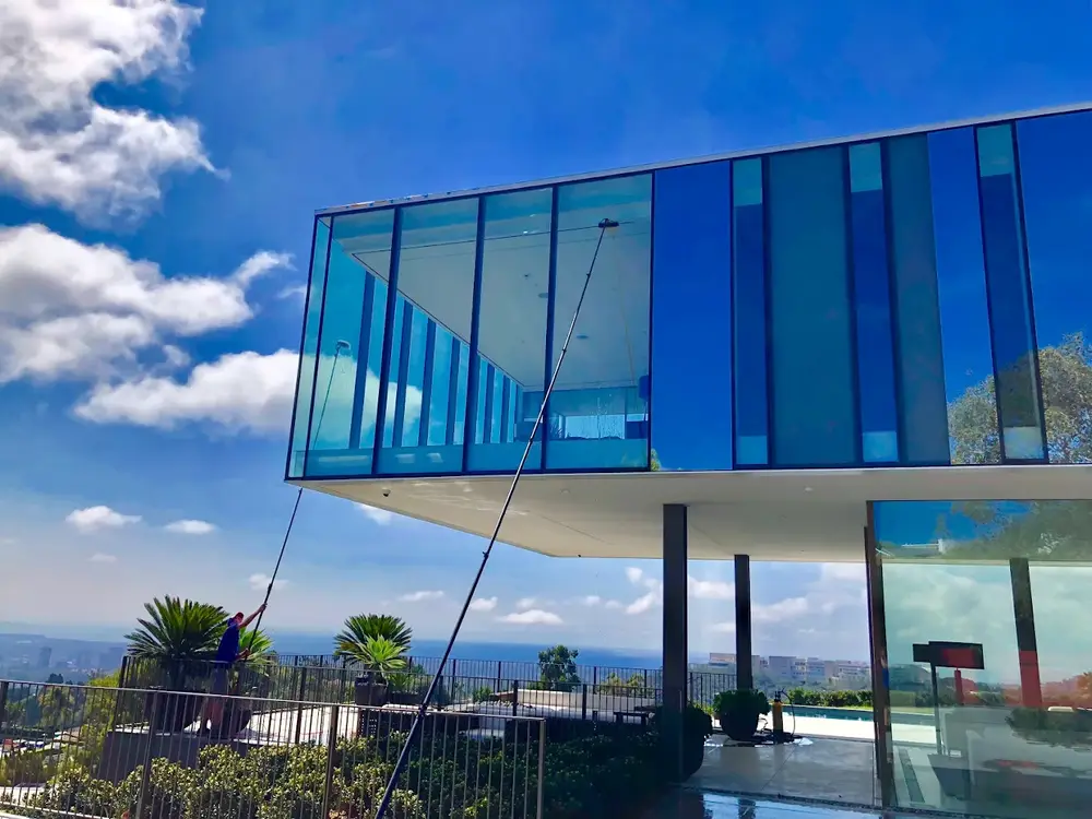 Technician cleaning windows on large Los Angeles estate