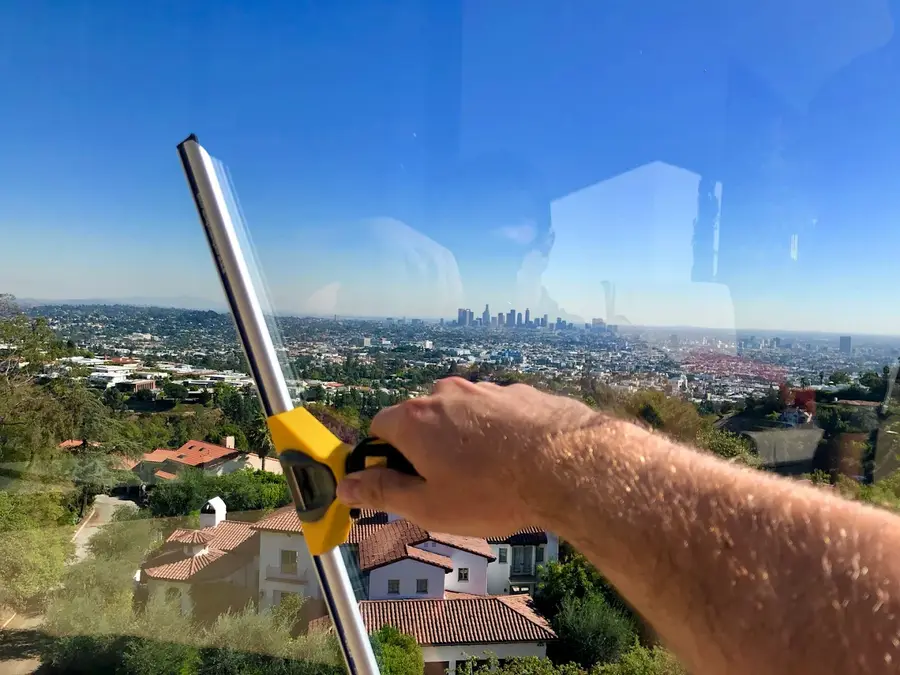 Technician cleaning glass with downtown LA skyline view
